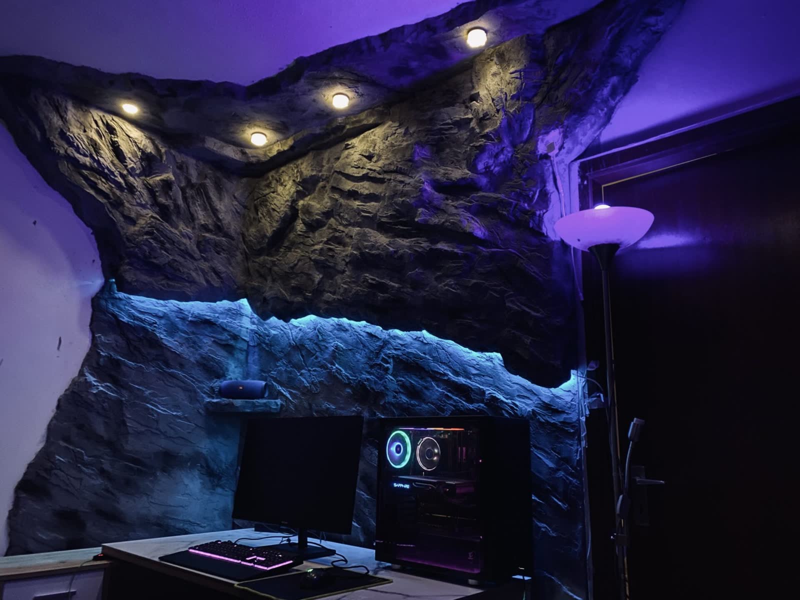 Gaming-Zimmer mit Felswand bis zum Deckenvorsprung und violetter LED-Beleuchtung