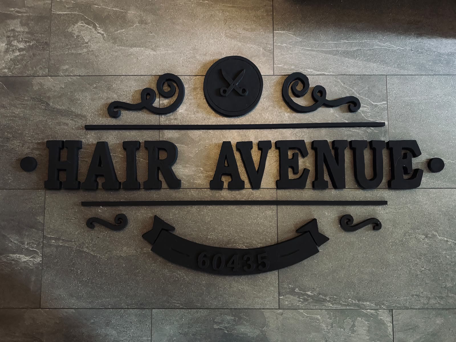 Vollständig lackierter Schriftzug „Hair Avenue” flach ausgelegt vor der Montage
