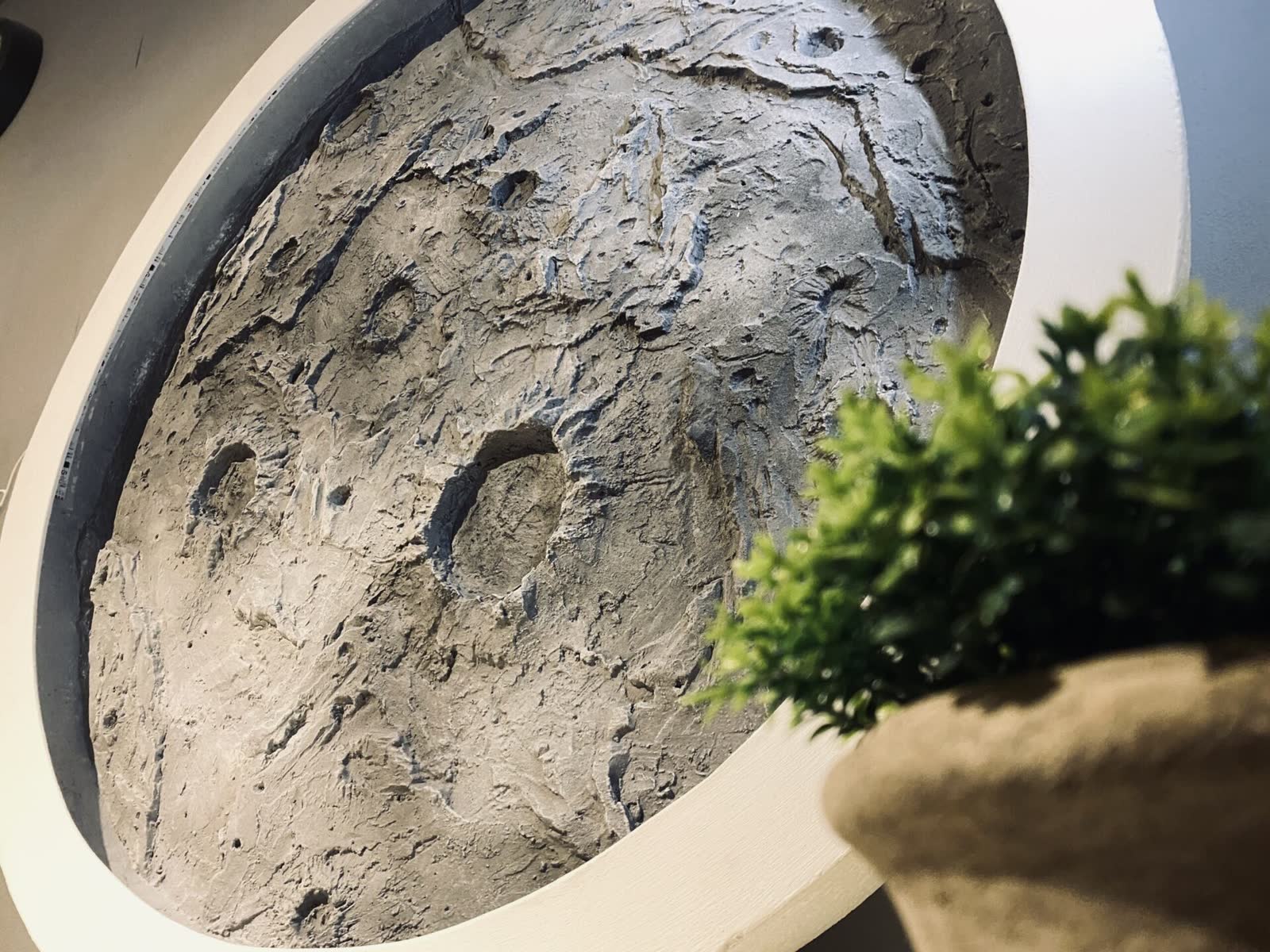 Rundes Kunststein-Wandbild mit Kraterstruktur in rundem Rahmen