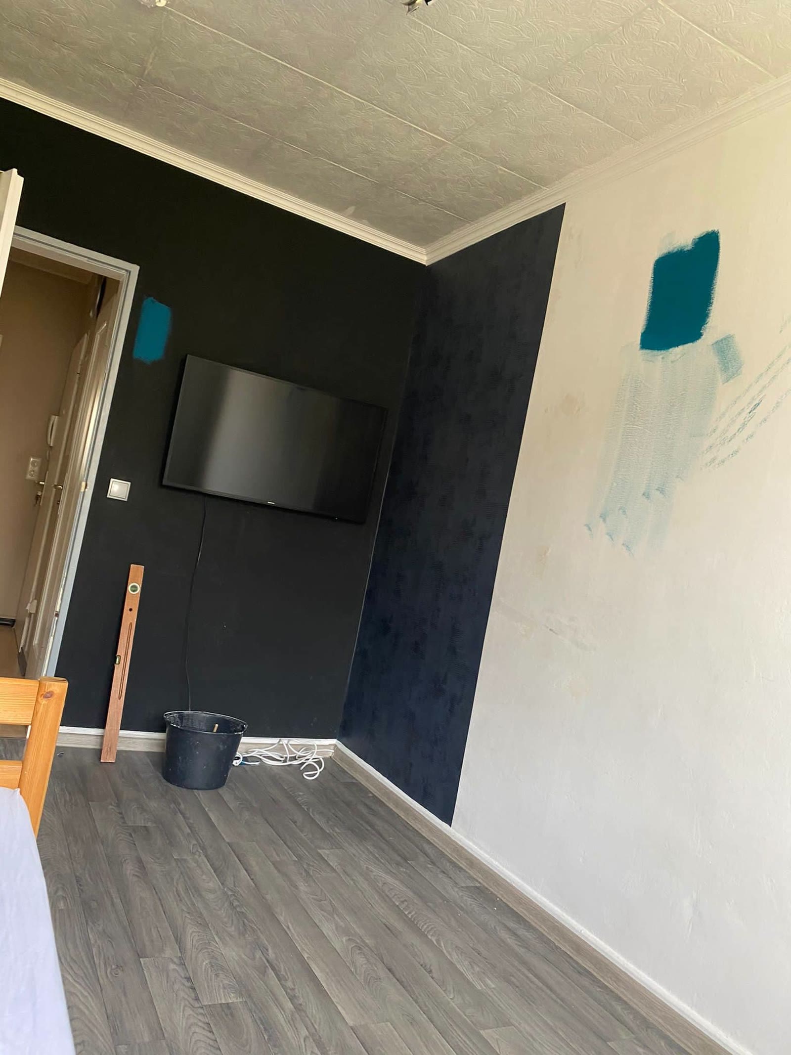 Die Wand vor der Umgestaltung: schwarz gestrichen mit ersten Farbtests in Blau