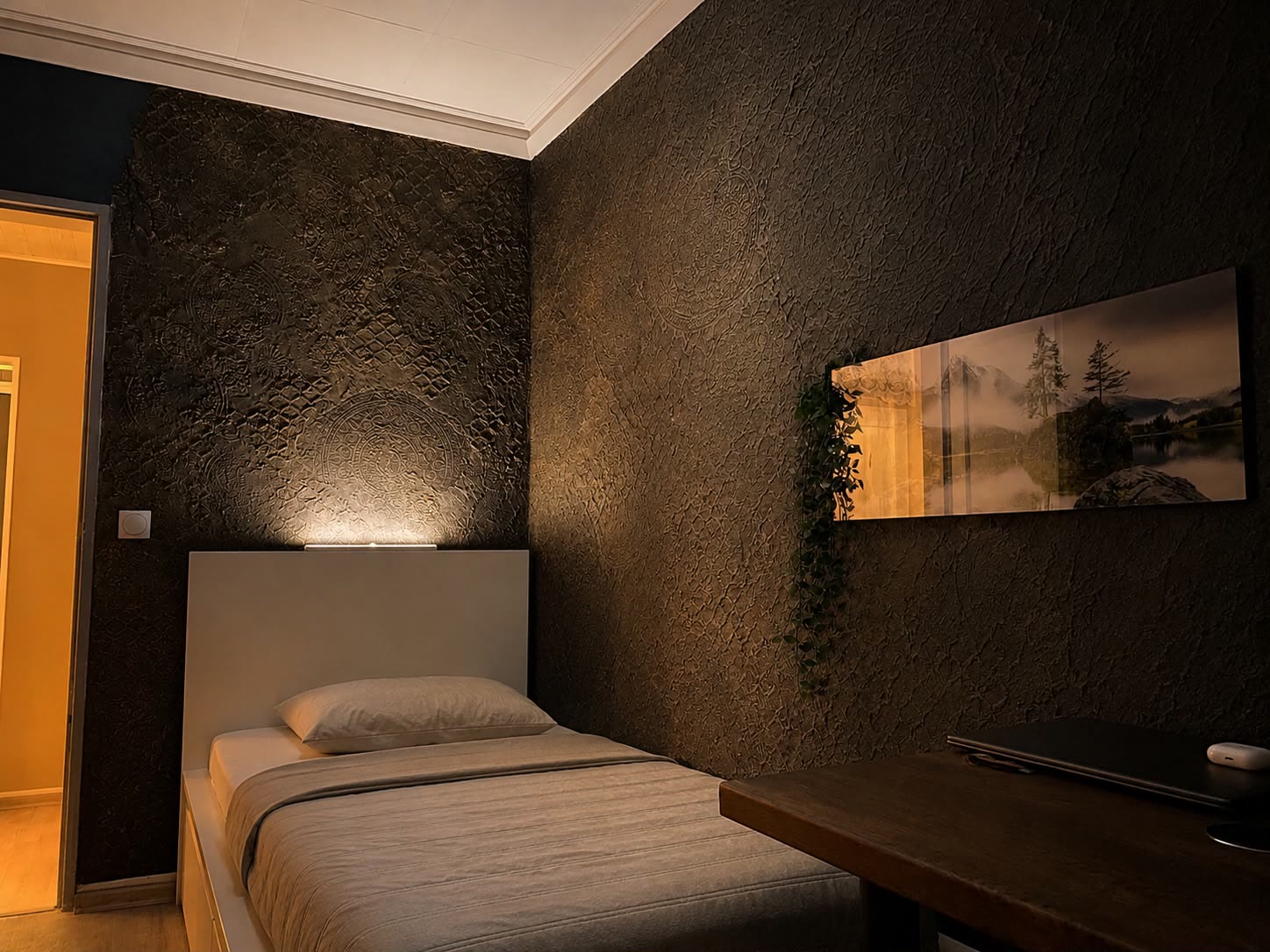 Schlafzimmerwand mit kreisrundem Ornamentrelief und warmer Beleuchtung hinter dem gemachten Bett