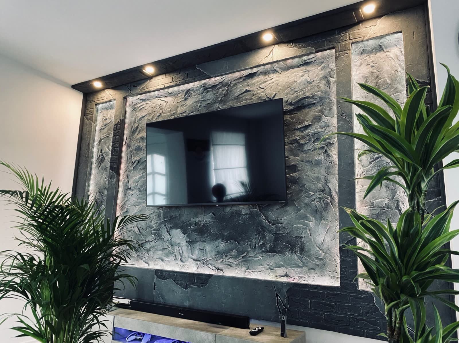 Kunststein-TV-Akzentwand in Felsoptik mit LED-Beleuchtung und Zimmerpflanzen