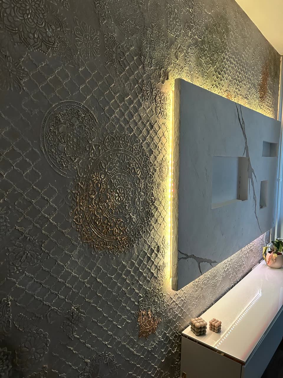 Seitenansicht einer vorgesetzten Kunststein-TV-Wand mit LED-Beleuchtung und Mandala-Reliefmuster