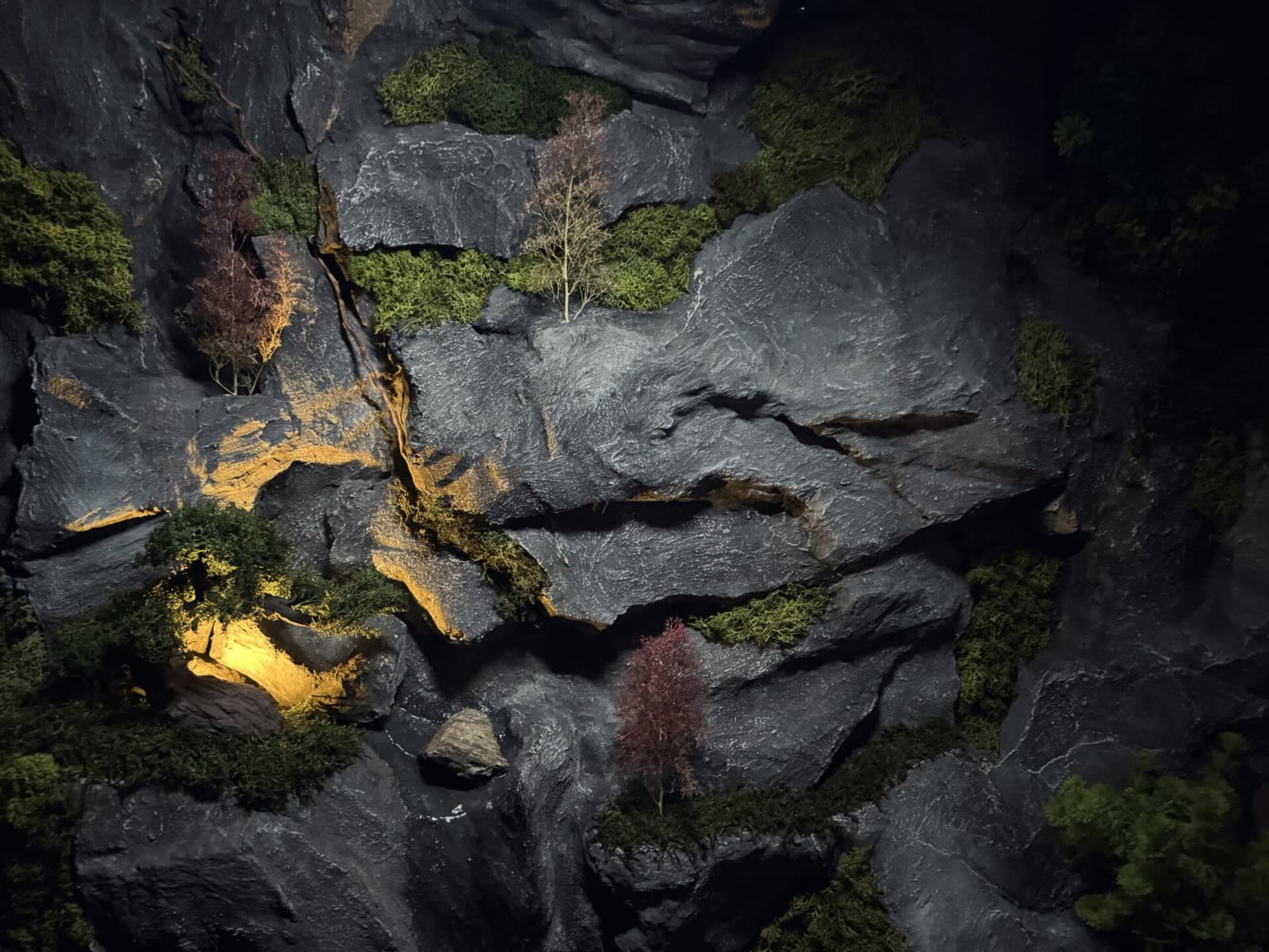 Kunststein-Wasserfallwand mit Moosbewuchs und warmer Akzentbeleuchtung