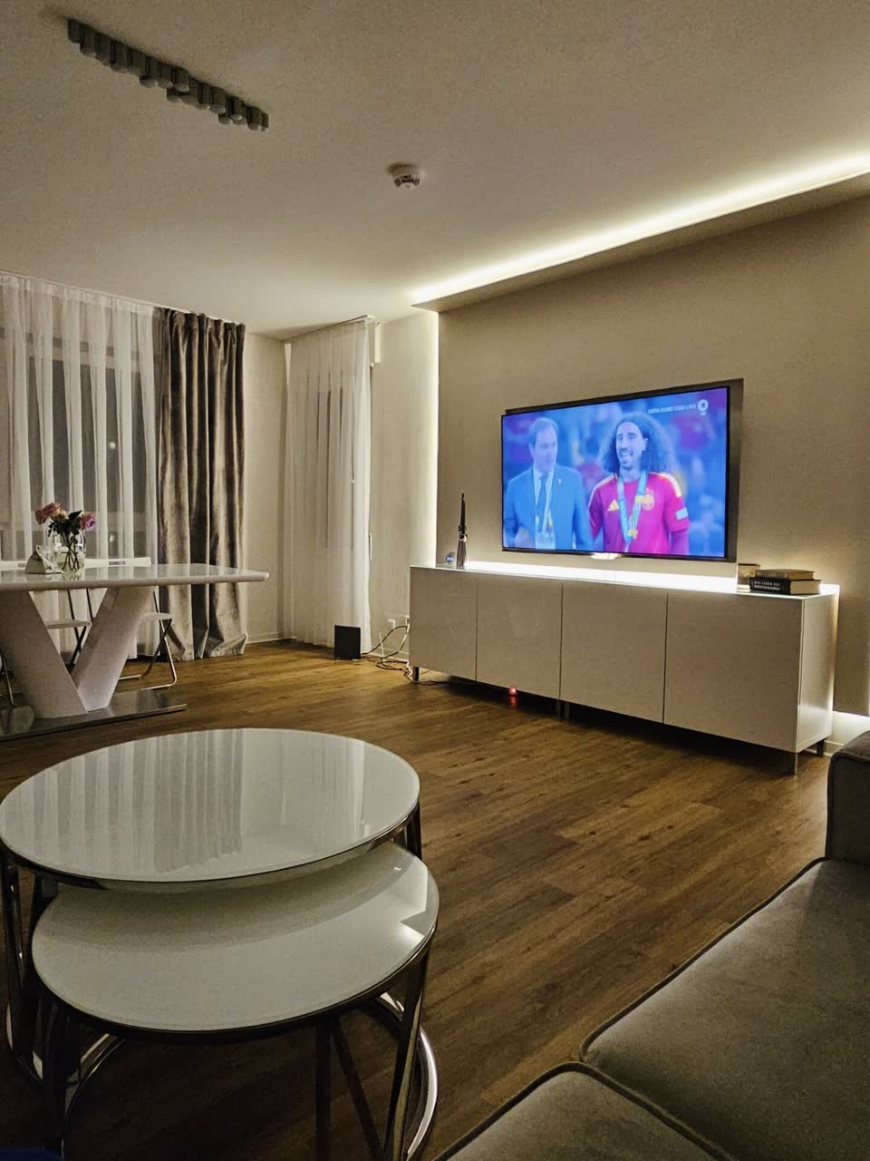 Wohnzimmer mit weißer TV-Akzentwand und warmer indirekter Beleuchtung